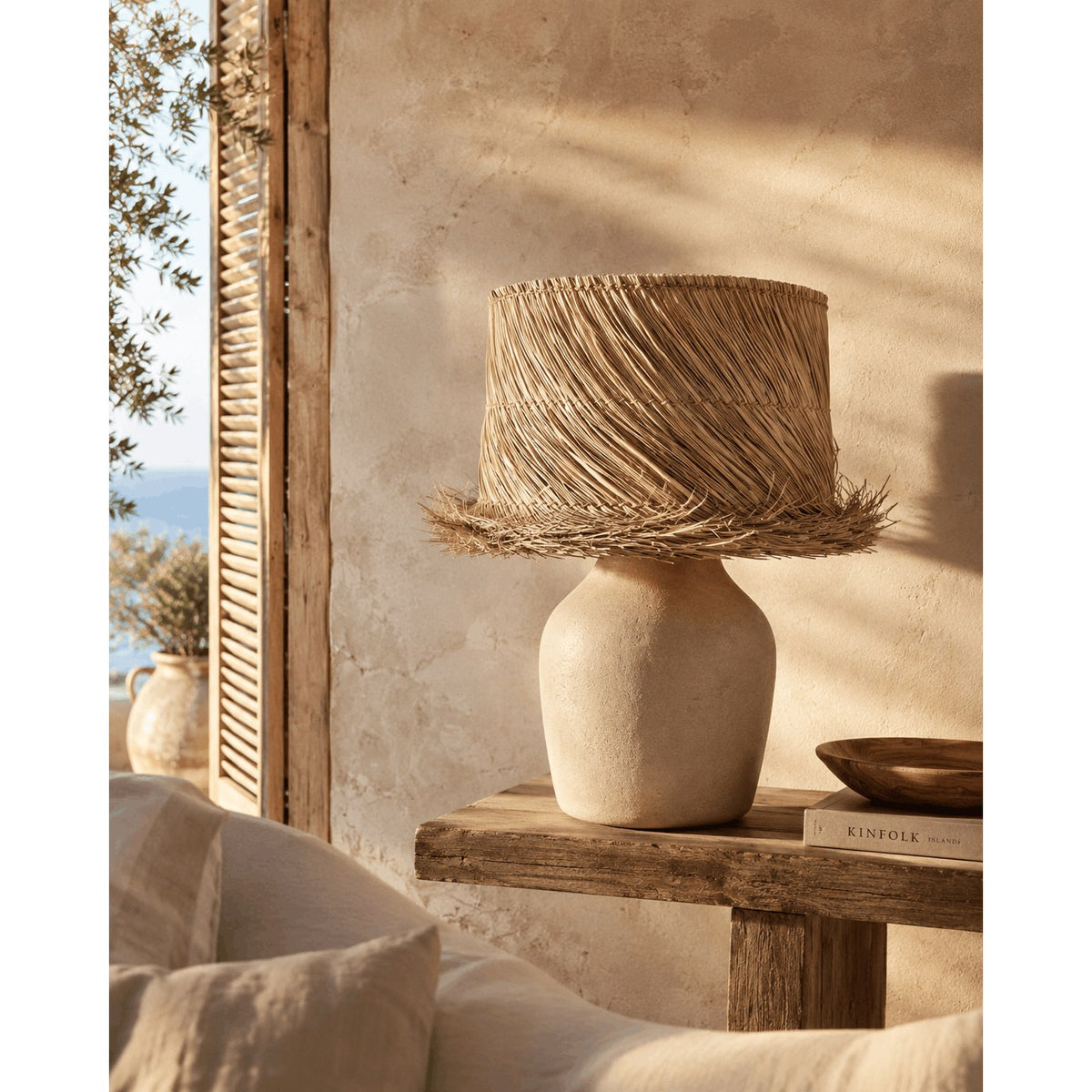 Abat-jour en pandan naturel sur un pied de lampe clair en forme de jarre non fourni posé sur une console en bois brut