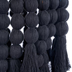 Détail des boules de coton noir enfilées en rangs et terminées par des pompons du lustre Nomad