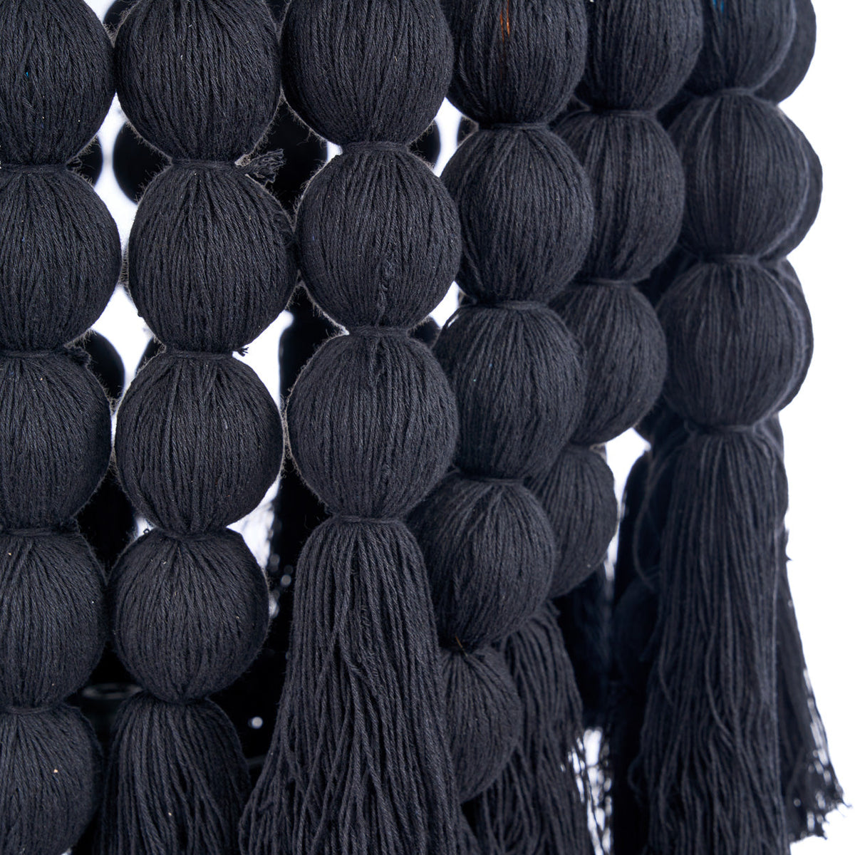 Détail des boules de coton noir enfilées en rangs et terminées par des pompons du lustre Nomad