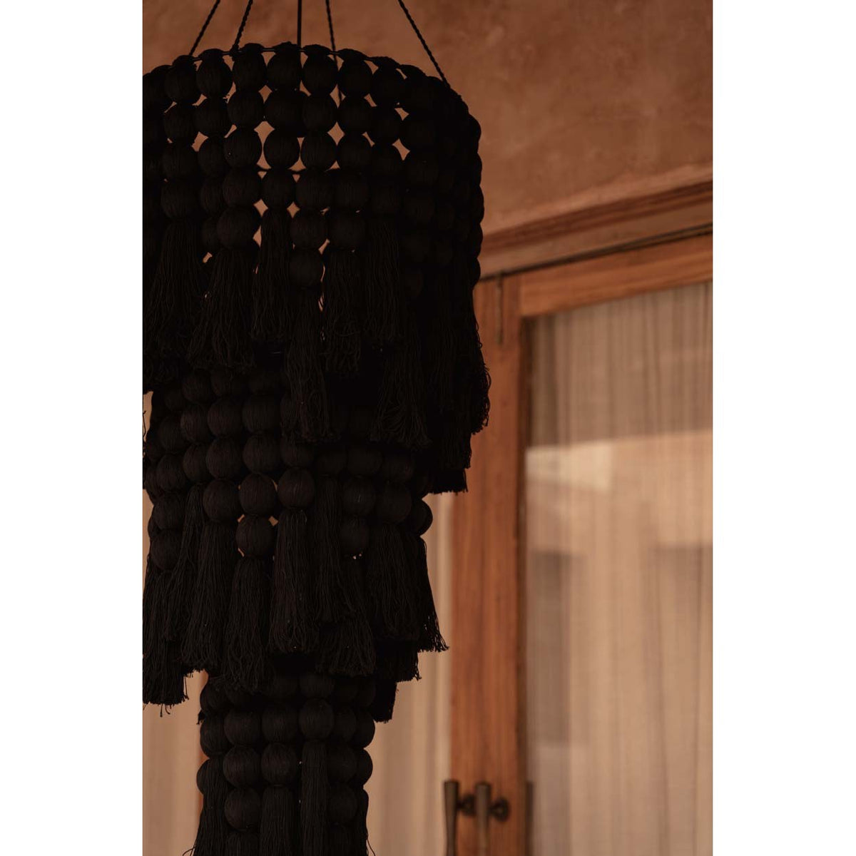 Abat-jour de lustre Nomad en coton noir vu de près devant une fenêtre en bois voilée