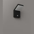 Applique extérieure Fiss éteinte sur un mur gris tête inclinée au-dessus d'un boîtier noir à détecteur