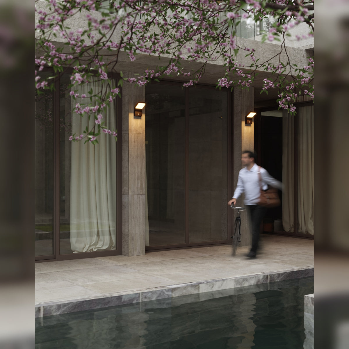 Deux appliques Fiss allumées sur les piliers d'une façade vitrée au bord d'une piscine