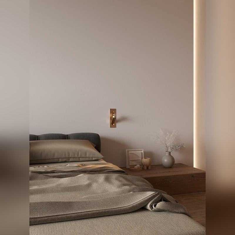 Chambre avec applique liseuse Libra teinte laiton vieilli au mur entre le lit et la table de chevet