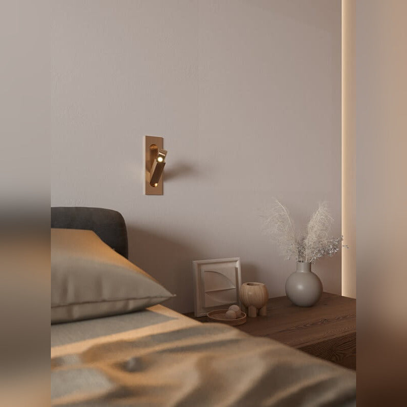 Applique liseuse Libra teinte laiton vieilli encastrée au mur près d'une table de chevet bras orienté vers le lit