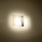 Applique Azalia allumée avec ses deux sources diffusées derrière le verre blanc et un halo sur le mur