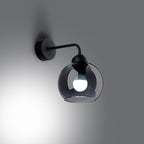 Applique Alino allumée avec ampoule visible à travers le verre fumé et lumière sur le mur