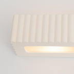 Gros plan de la fente lumineuse de l'applique Rigata en céramique blanche allumée