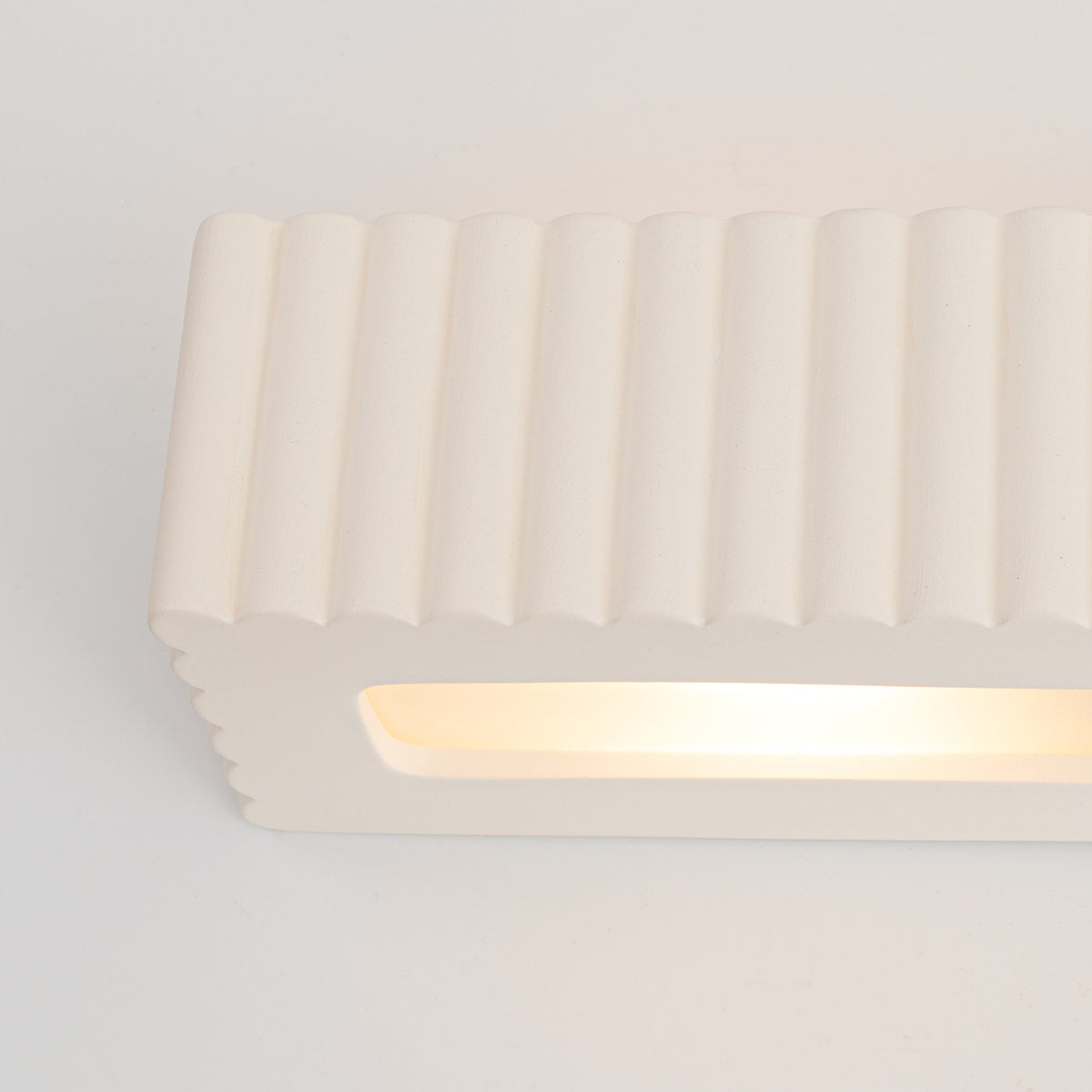 Gros plan de la fente lumineuse de l'applique Rigata en céramique blanche allumée