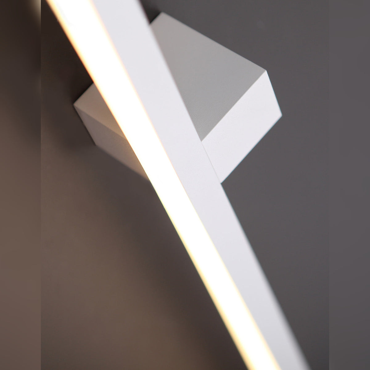 Détail de l'applique Finger blanche allumée avec son diffuseur continu et son boîtier carré sur un mur gris