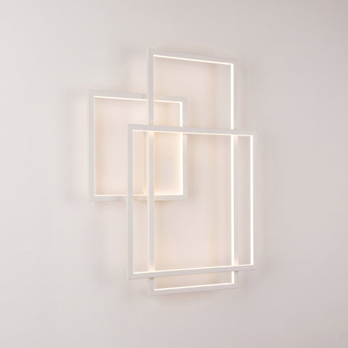 Applique murale Geometric LED en métal blanc allumée, trois cadres rectangulaires superposés posés à la verticale sur un mur clair