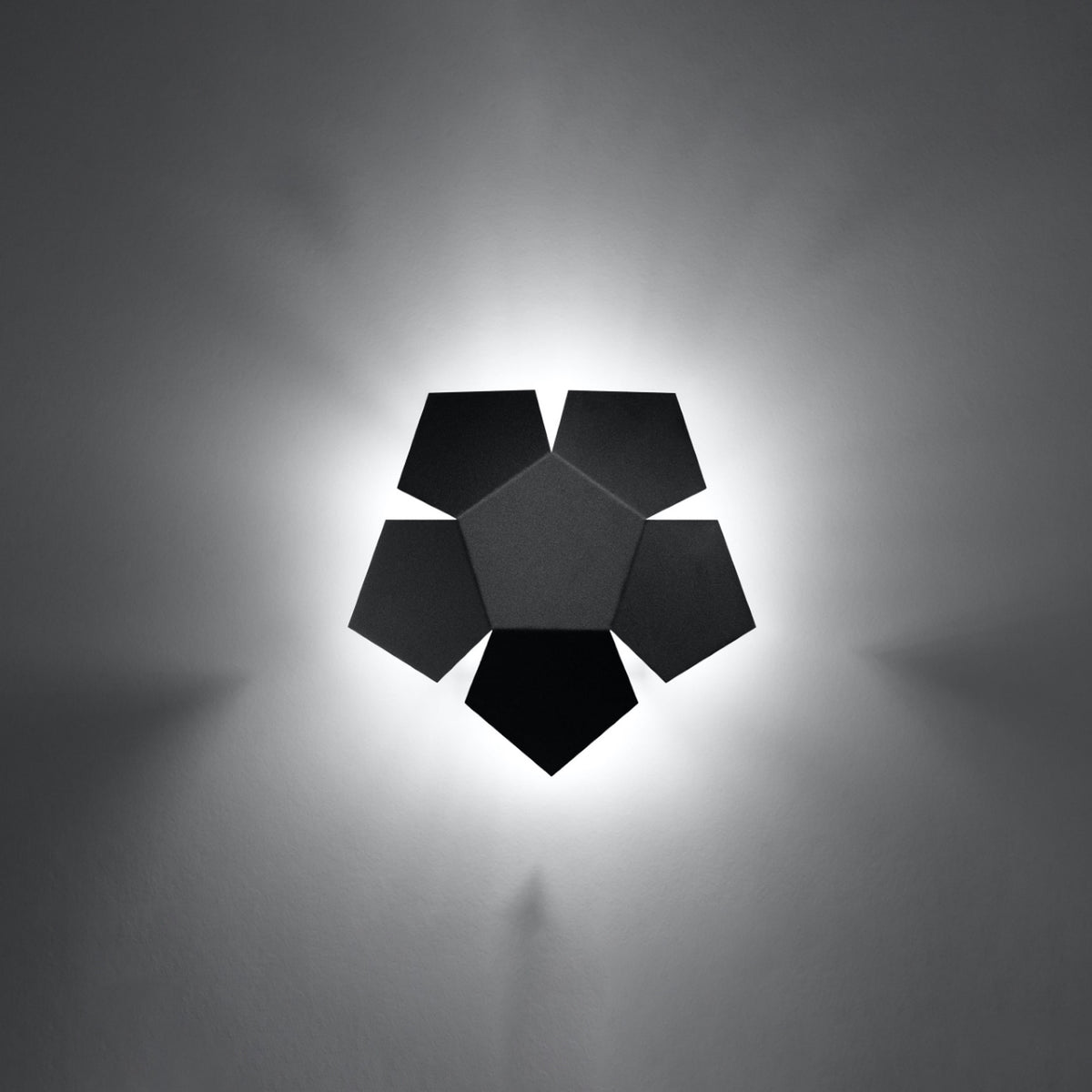 Applique murale Penta allumée entourée d'un halo de lumière sur un mur gris