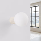 Applique murale Halo boule opale beige posée sur un mur clair