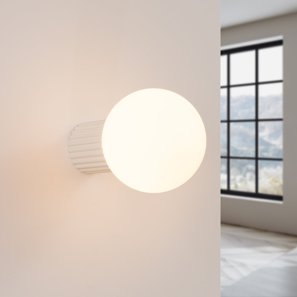 Applique Halo laque beige allumée sur un mur clair près d'une fenêtre