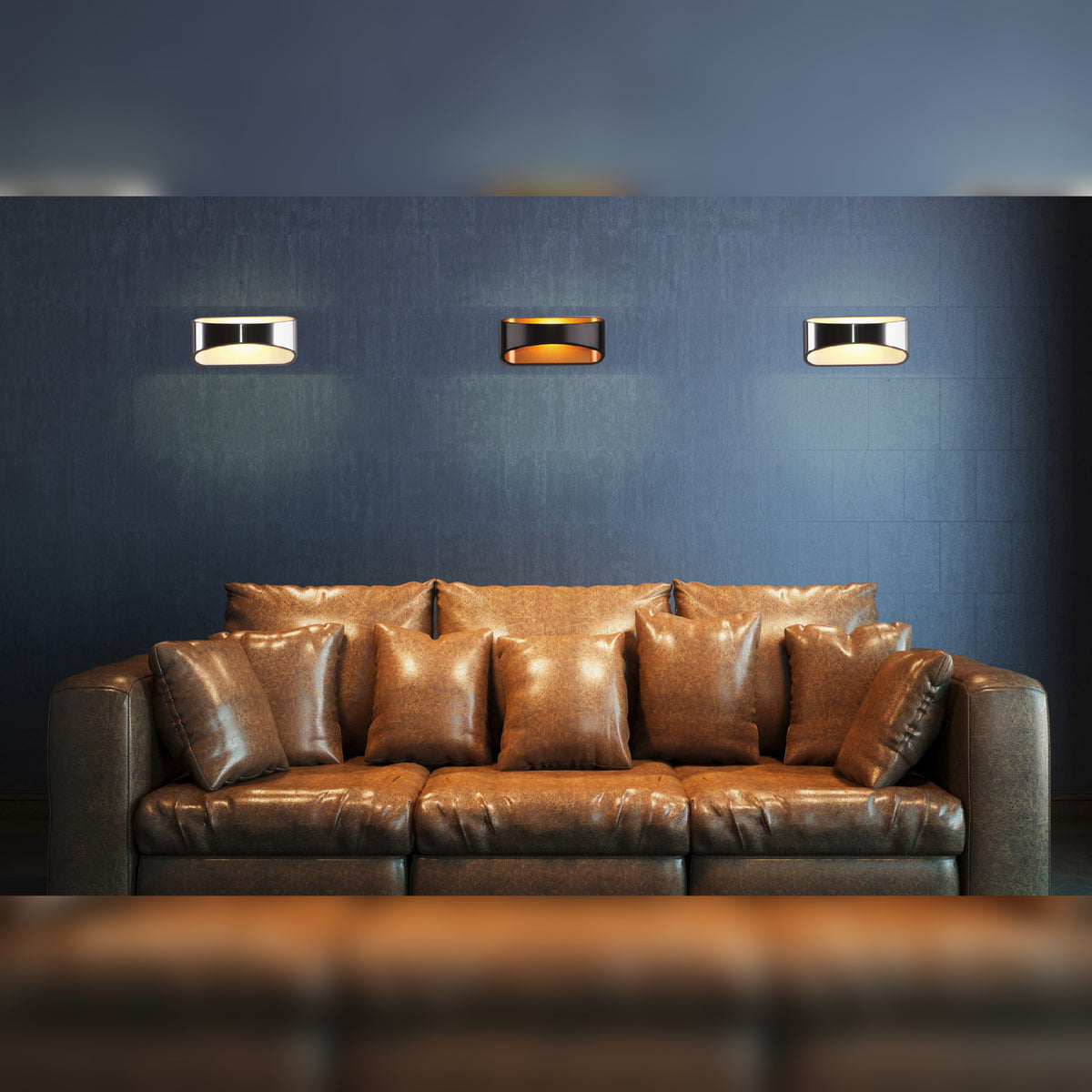 Deux appliques Hugo chromées et une version noire à intérieur doré au-dessus d'un canapé brun sur un mur bleu nuit