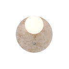 Applique murale Lando vue de face disque de travertin crème et globe blanc allumé avec son bouton de réglage