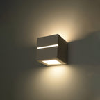Applique Leo Line allumée sur un mur sombre avec un halo vers le haut et une nappe de lumière vers le bas