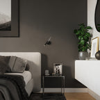 Applique Axil noire au-dessus d'une table de chevet en métal dans une chambre aux murs sombres