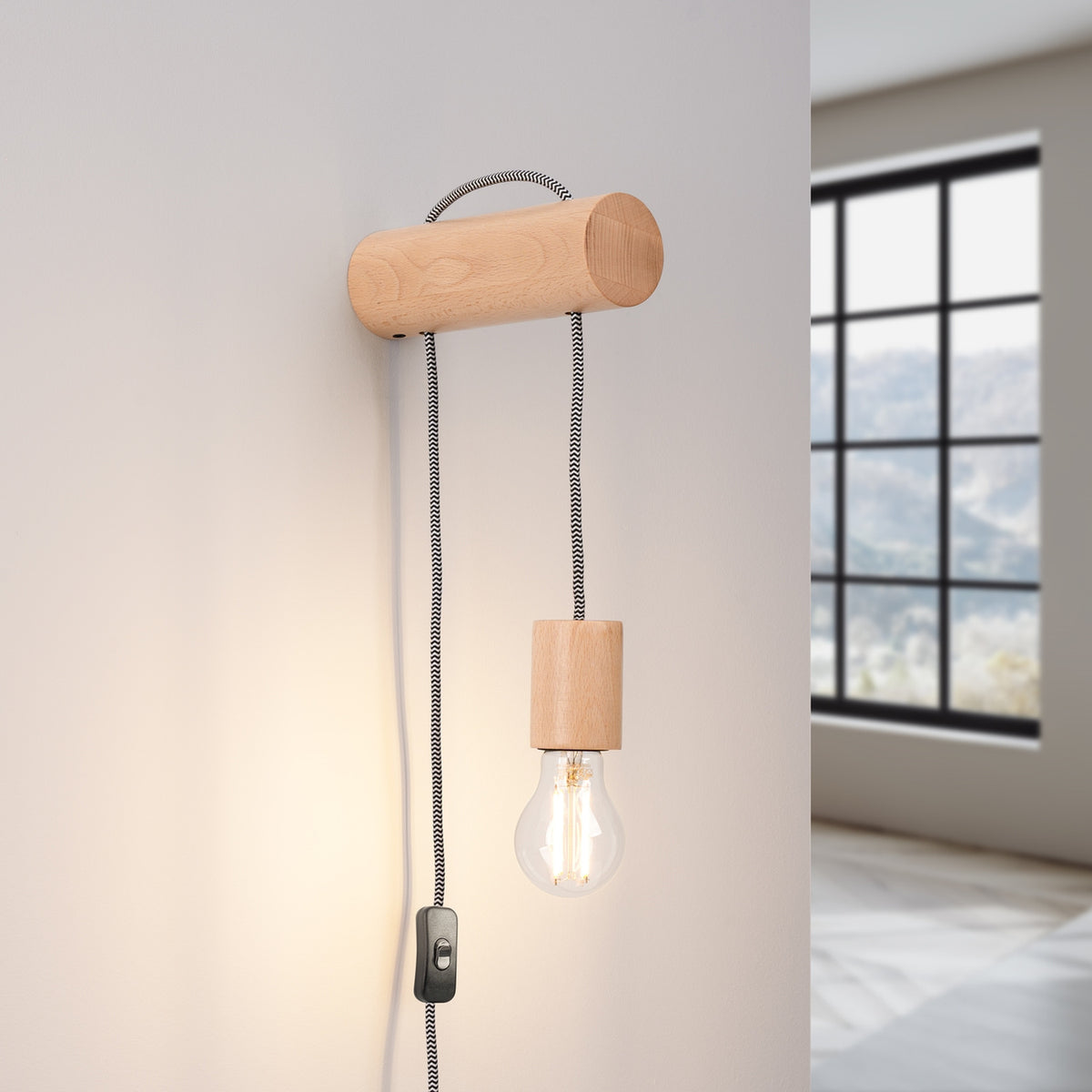Applique Nimbi allumée sur un mur blanc avec son ampoule à filaments