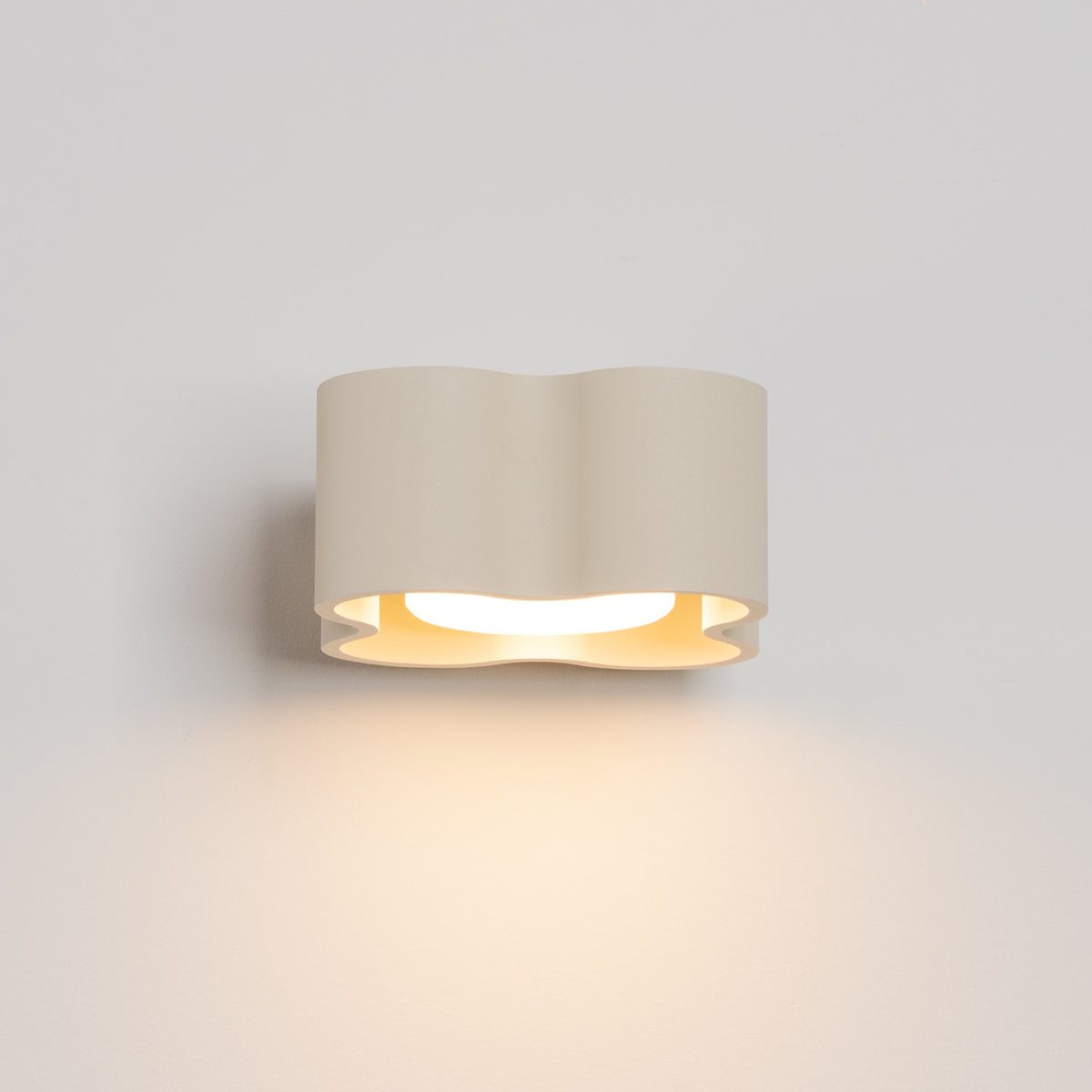 Applique Ovio laque beige vue de face allumée avec son halo de lumière vers le bas