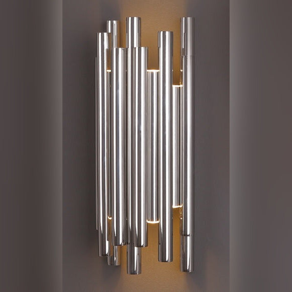 Applique murale Organic Chromé allumée sur un mur gris avec un halo de lumière chaude