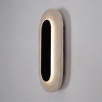 Applique murale Travertino vue de trois quarts anneau de lumière entre la plaque ovale noire et le travertin