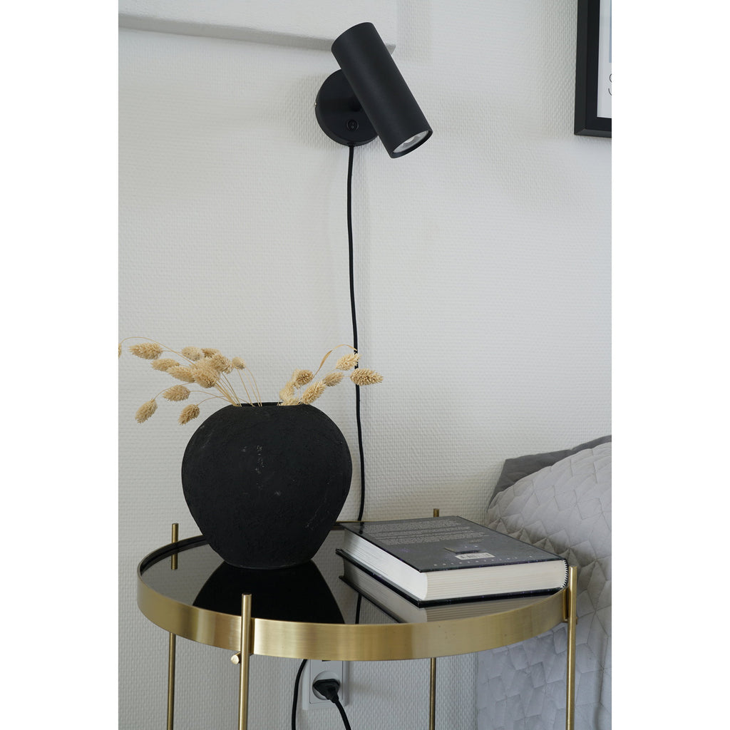 Applique murale Paris noire au-dessus table d'appoint dorée, ambiance chambre contraste