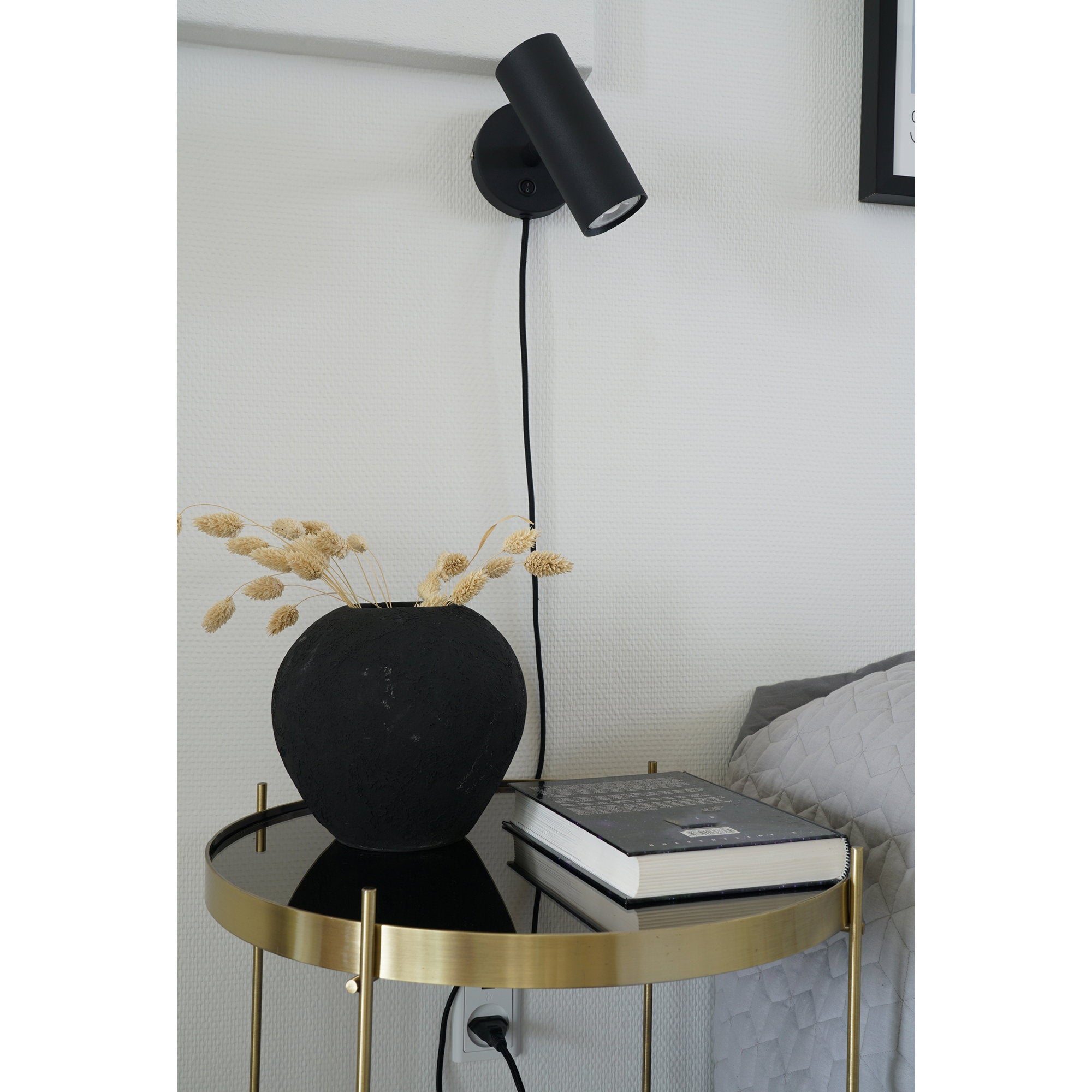 Applique murale Paris noire au-dessus table d'appoint dorée, ambiance chambre contraste