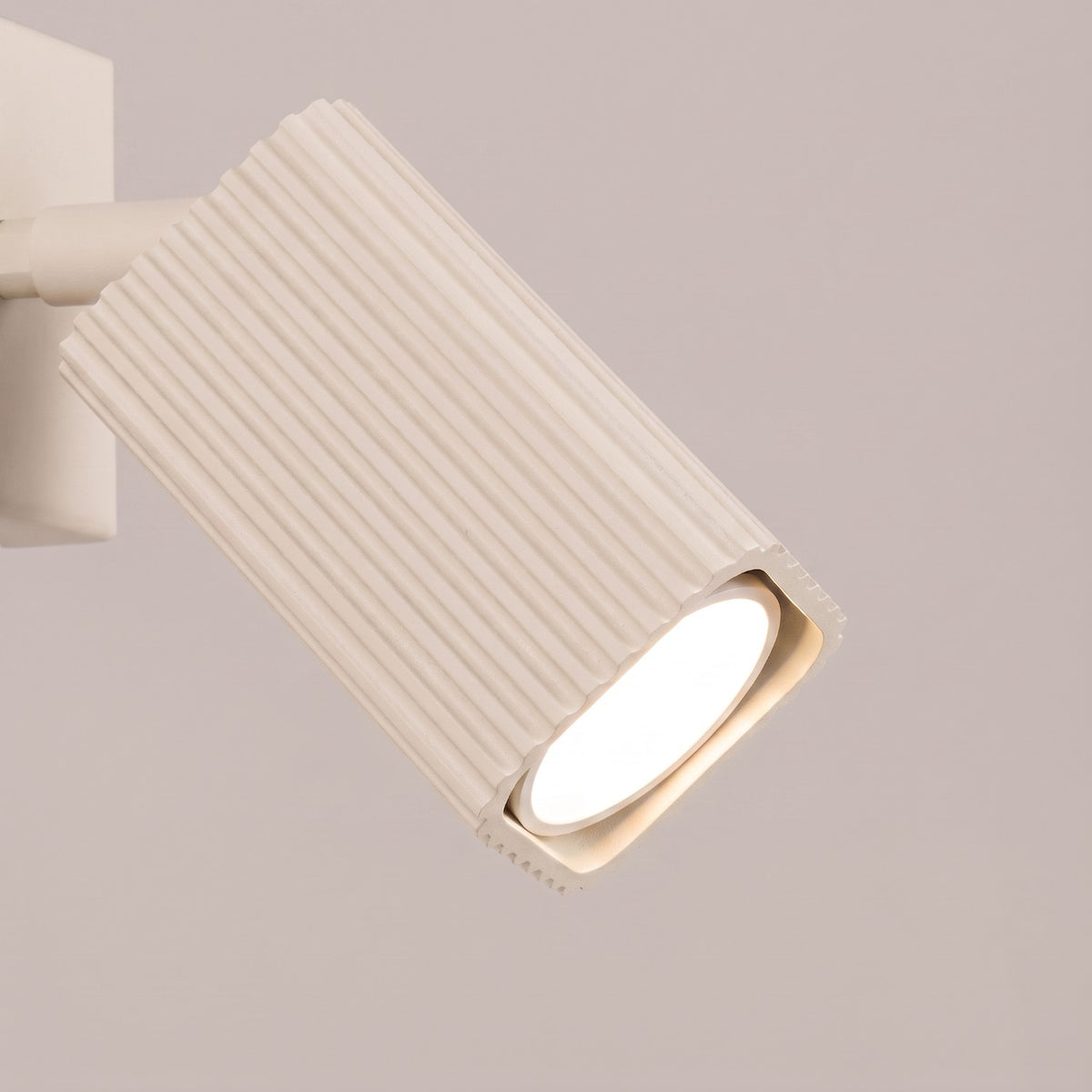 Gros plan sur le spot cannelé allumé de l'applique Rayo laque beige