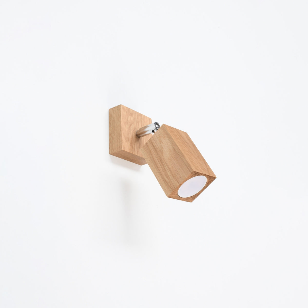 Applique Keke en chêne fixée sur un mur blanc avec sa platine carrée et son articulation métallique