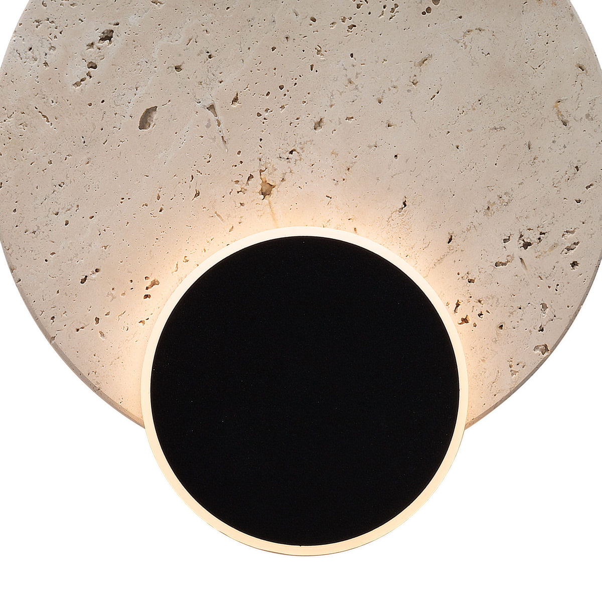 Détail du travertin alvéolé éclairé par l'anneau lumineux du disque noir de l'applique Travertino