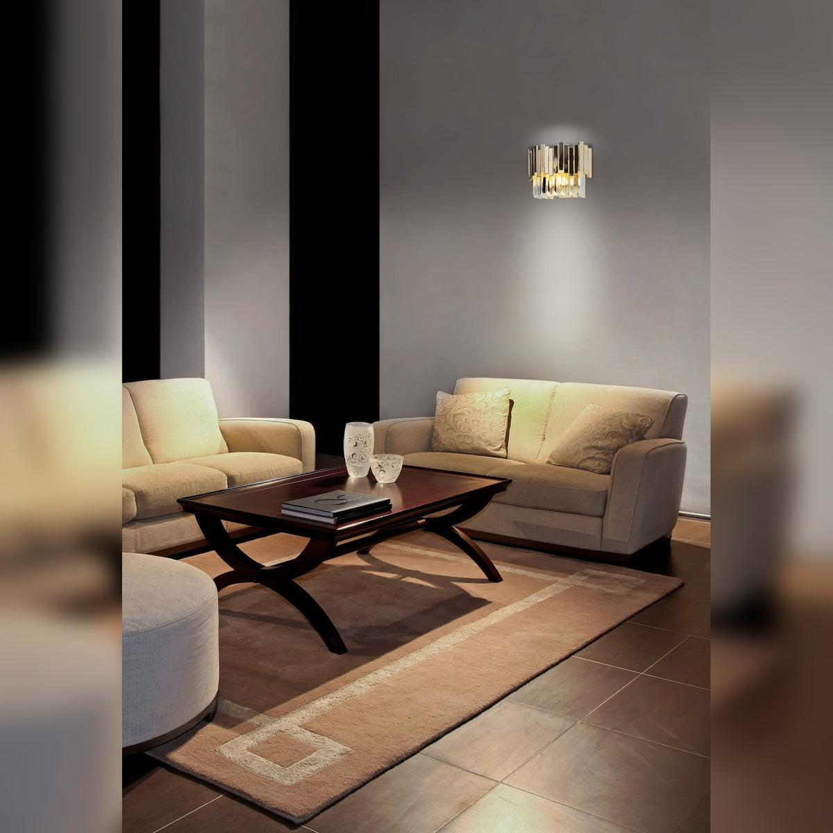 Applique murale Trend allumée sur le mur gris d'un salon au-dessus d'un canapé beige avec sa lumière vers le haut et vers le bas