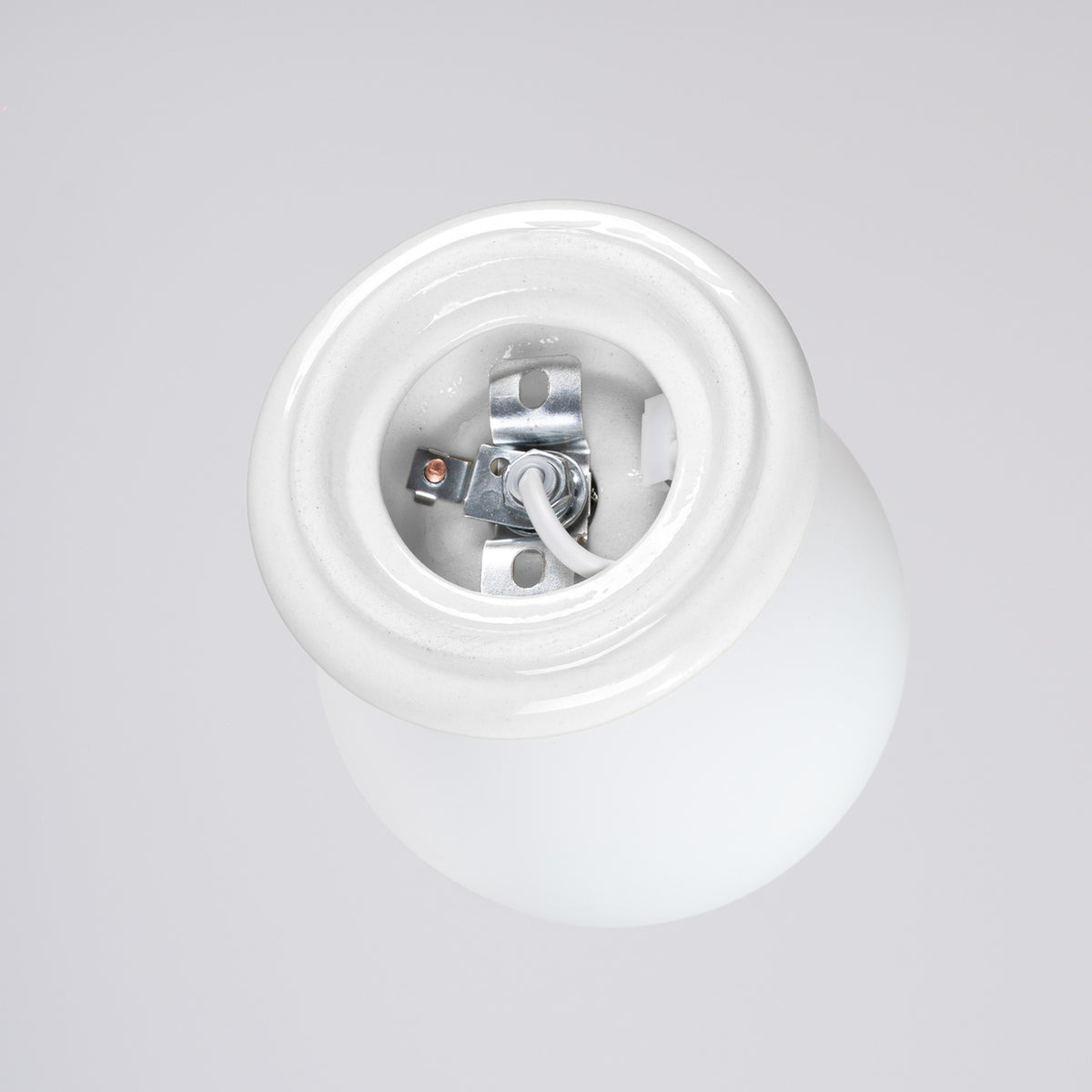 Arrière du socle en céramique émaillée blanche avec sa platine de fixation percée et son câble
