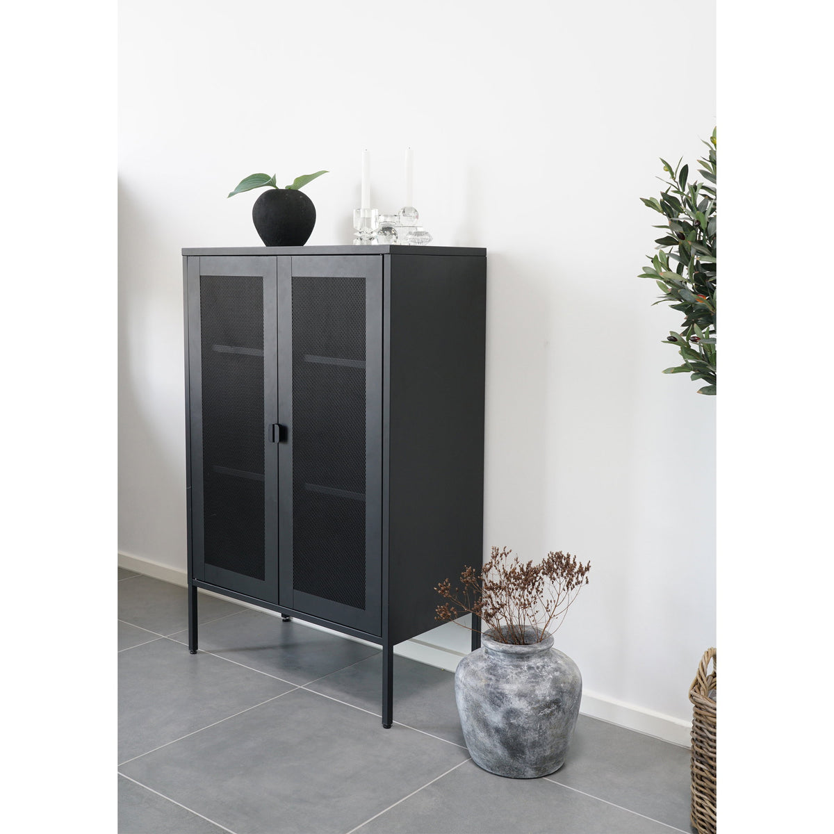 Armoire Melbourne noire contre un mur blanc avec un vase et deux bougeoirs en verre sur le plateau