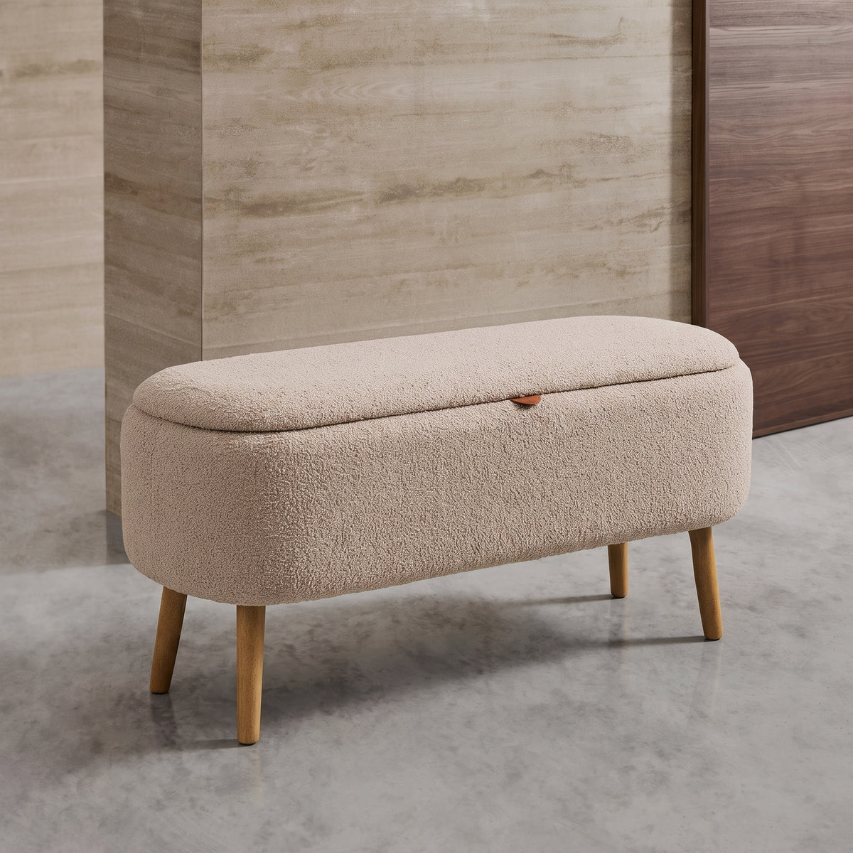 Banc coffre Harlow bouclé taupe dans une entrée, devant un mur en travertin et une porte en bois foncé