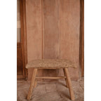 Banc Raffia vu de face devant un mur terracotta entre deux portes en bois
