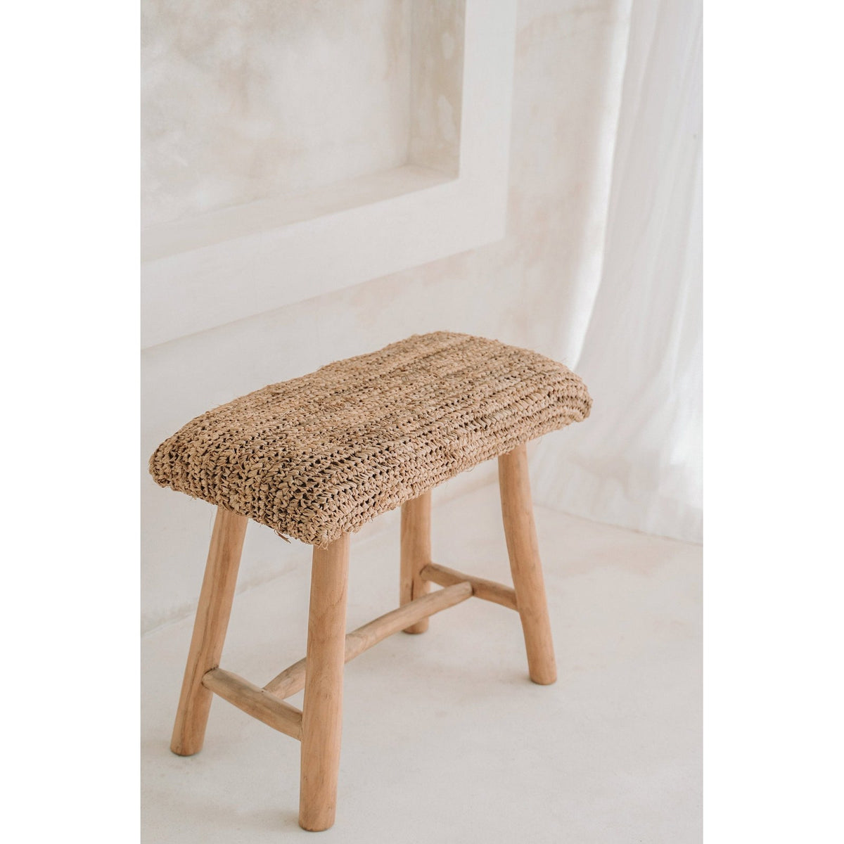 Banc Raffia vu en plongée dans une pièce blanche montrant le tressage ajouré de l'assise
