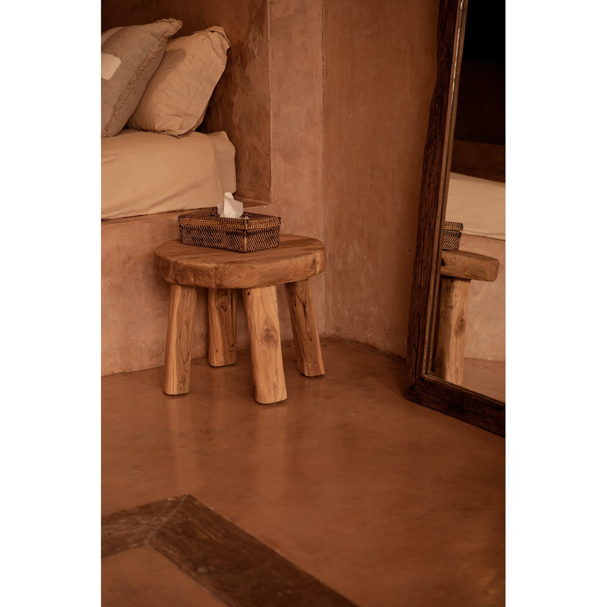 Boîte à mouchoirs en rotin sur un tabouret en bois massif à côté d'un lit et d'un grand miroir