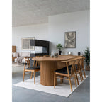 Salle à manger avec une table en bois à pied cannelé et la boîte en travertin naturel posée sur le buffet du fond