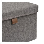 Détail de la languette caramel cousue et du tissu chiné d'une boîte Noto gris foncé