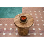 Bol en coco garni de fruits coupés sur une table d'appoint en bois au bord d'une piscine