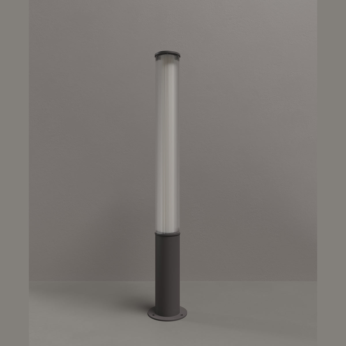 Borne d'extérieur Gardenia métal anthracite 115 cm éteinte devant un mur gris diffuseur cannelé et platine au sol