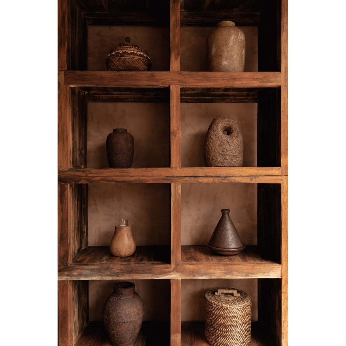 Bougeoir Totem en terre cuite brune dans une étagère en bois parmi des vases et des paniers