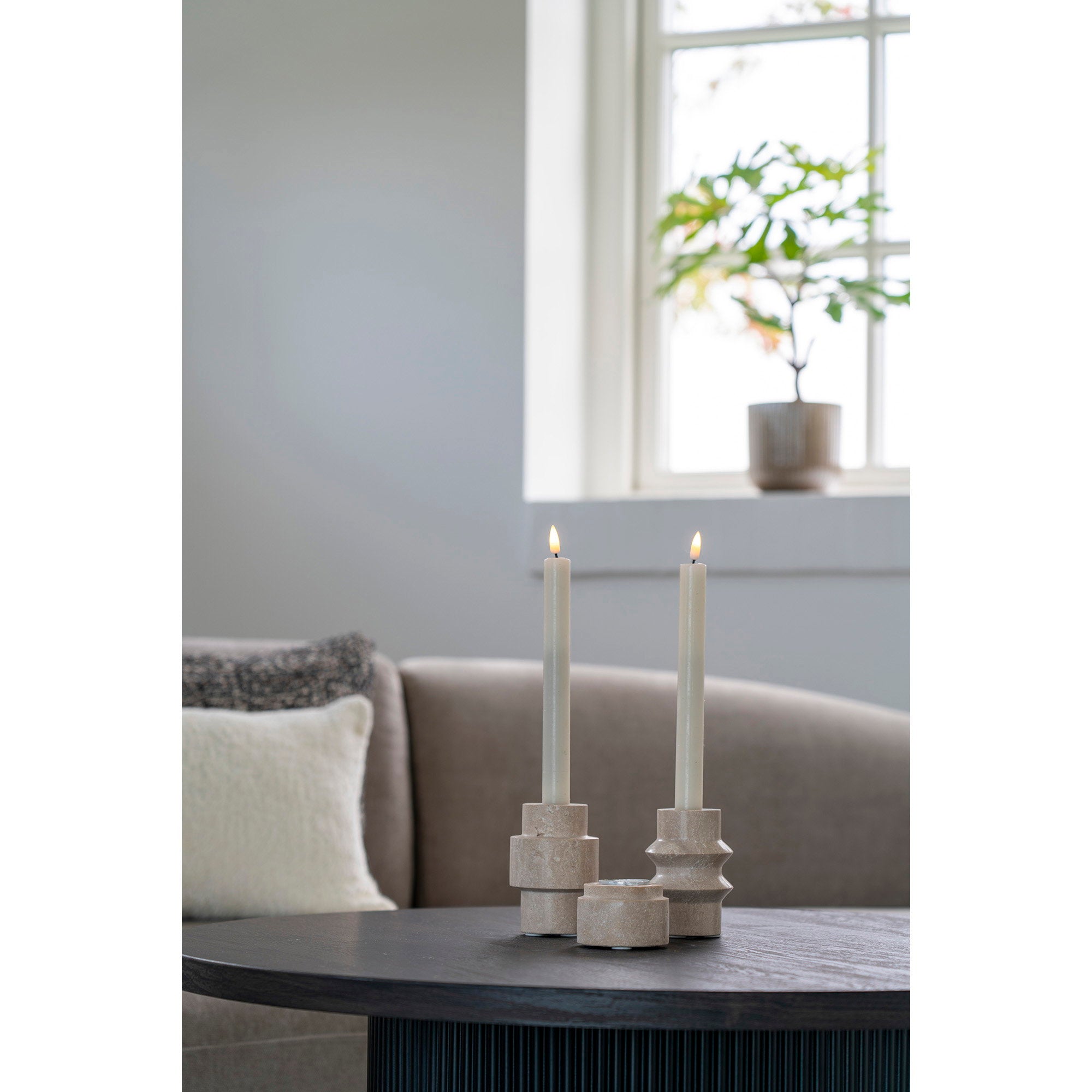 Duo bougeoirs travertin naturel bougies chandelles allumées table basse noire salon canapé taupe