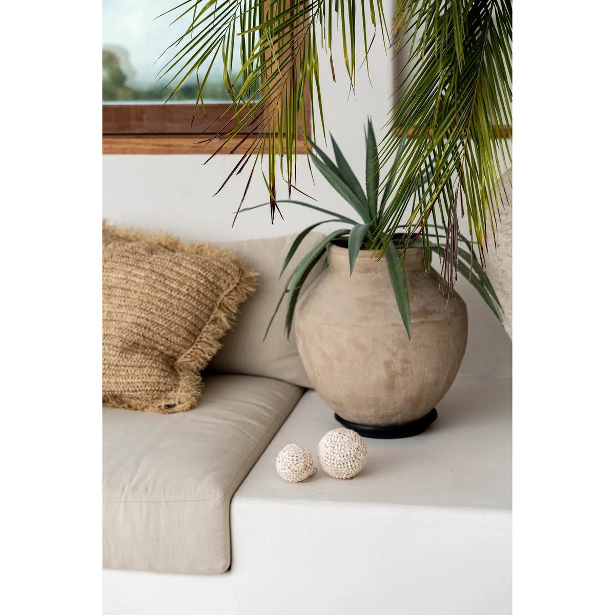 Boule décorative Bubble et une boule plus petite posées sur une banquette blanche près d'un vase en terre