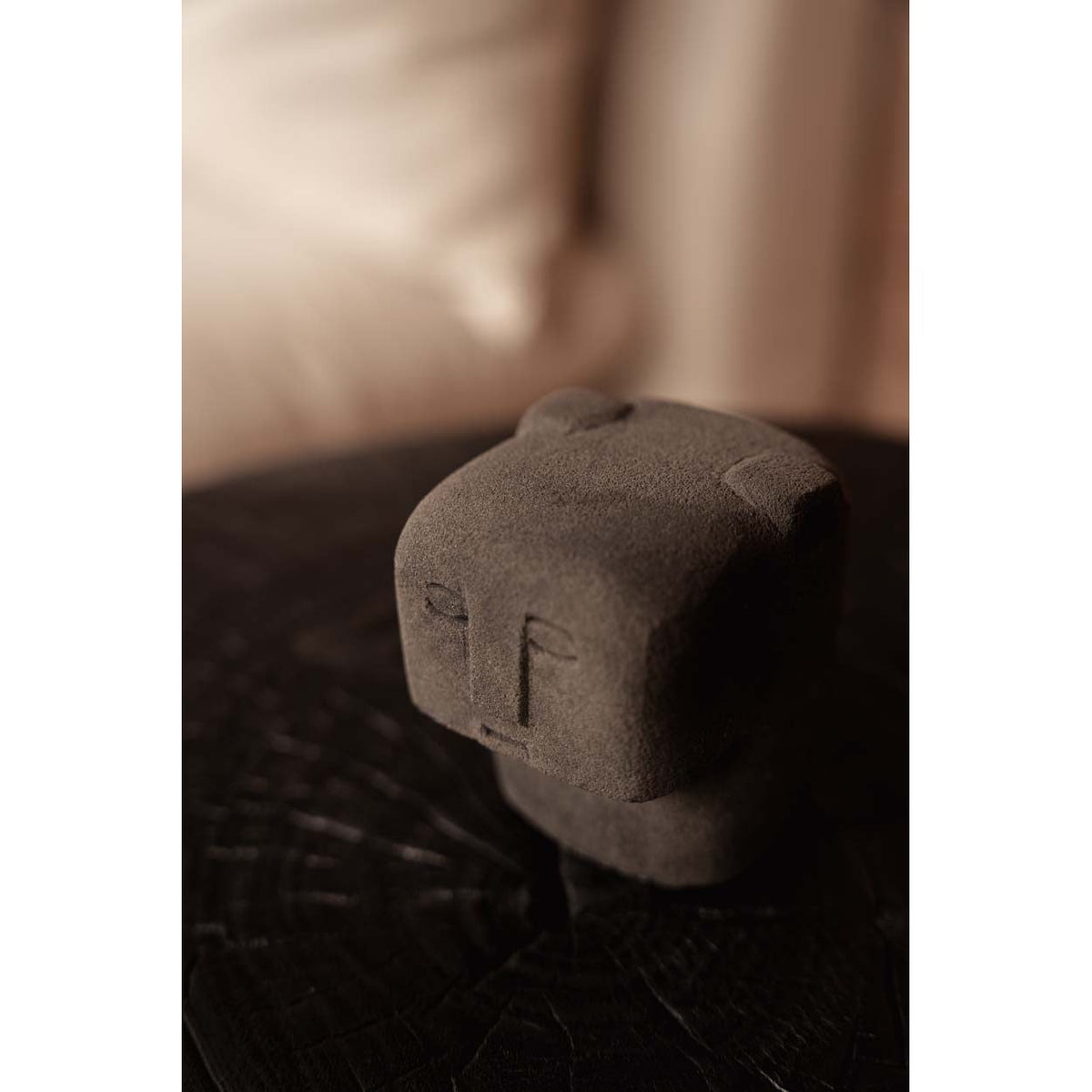 Buste Sumba à oreilles en grès gris vu en plongée sur une table en bois sombre