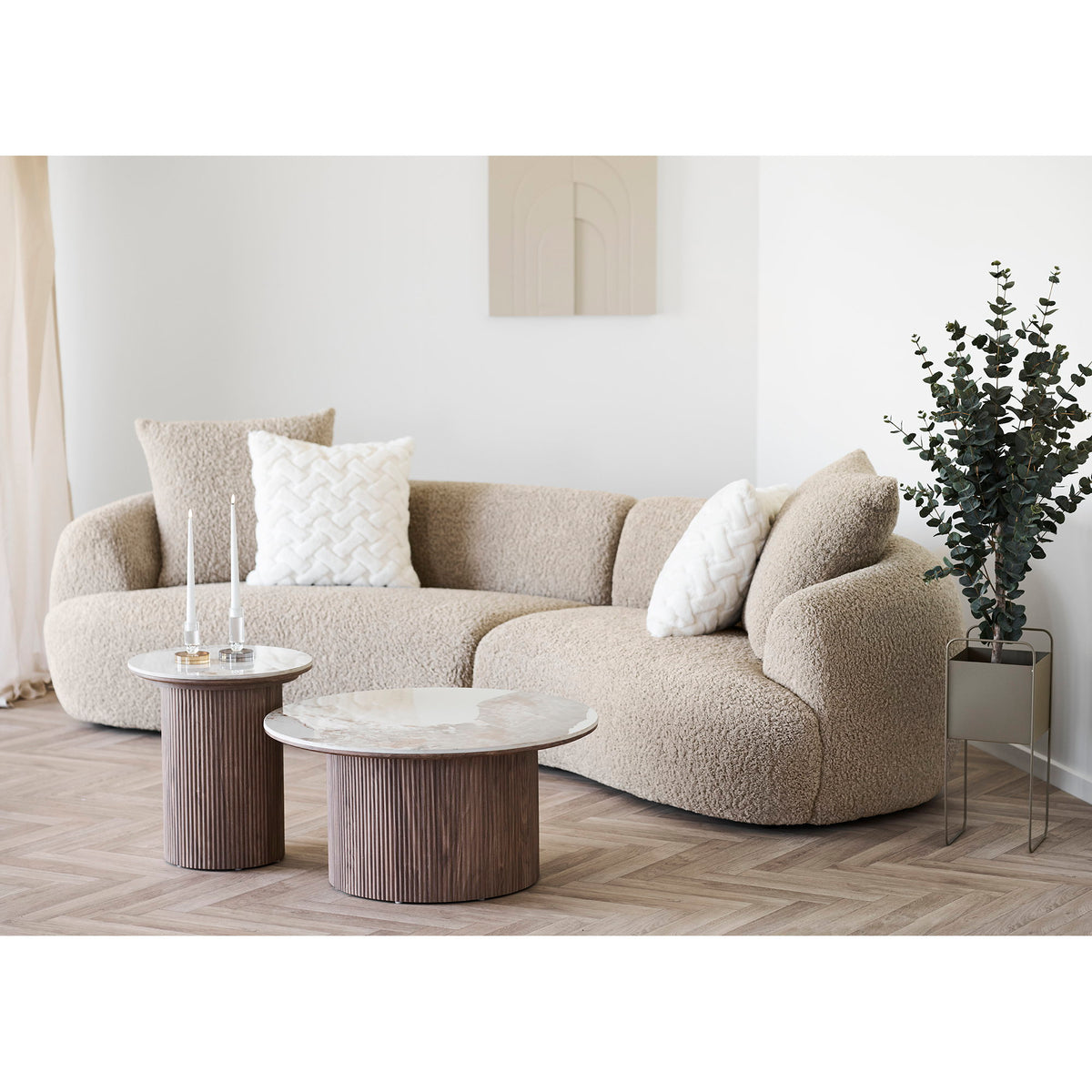 Cache-pot carré en acier taupe avec un eucalyptus au bout d'un canapé courbe en bouclette dans un salon