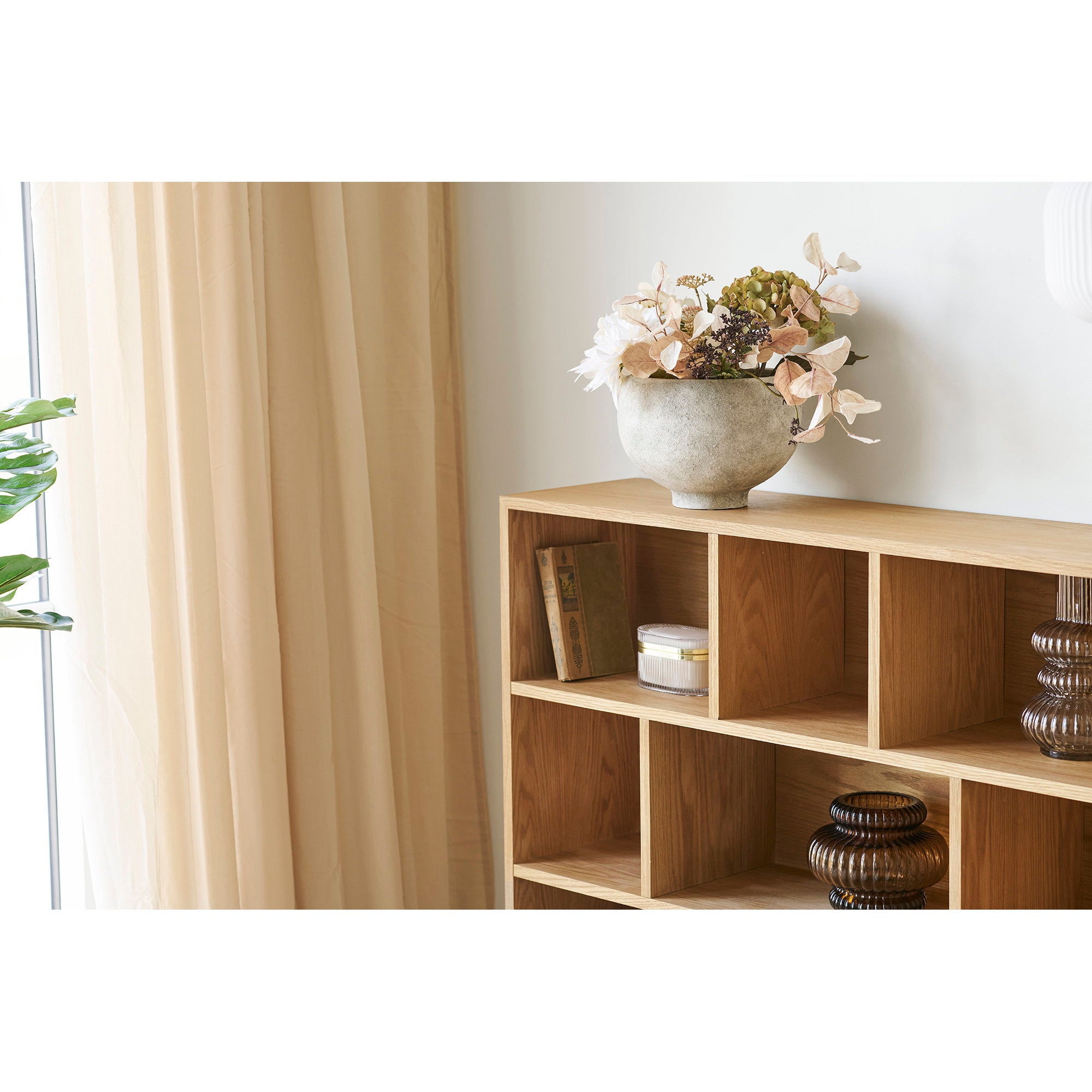 Cache-pot céramique grès gris avec fleurs séchées sur bibliothèque bois clair