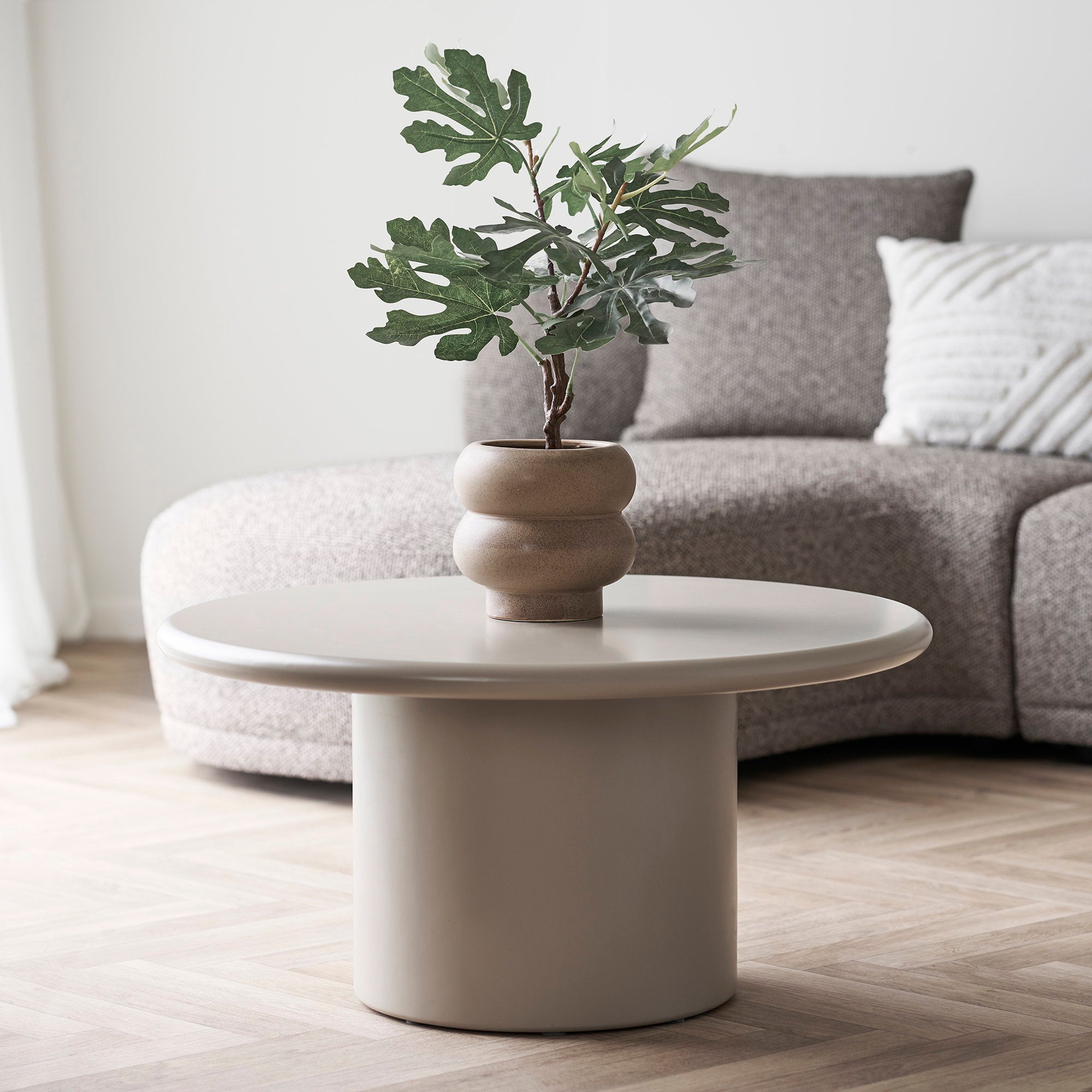 Cache-pot céramique marron sablé posé sur table basse salon minimaliste avec plante verte