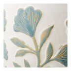 Détail d'une fleur en éventail en relief émaillée bleu céladon sur céramique blanche