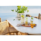 Cache-pot floral en céramique derrière une carafe et des verres ciselés sur une table claire